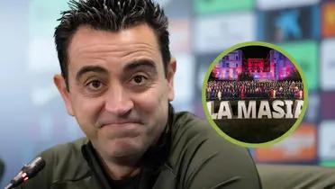 Xavi se sonríe en rueda de prensa, a su izquierda La Masía.
